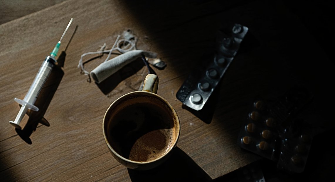 Шприц, кофе и медикаменты на столе